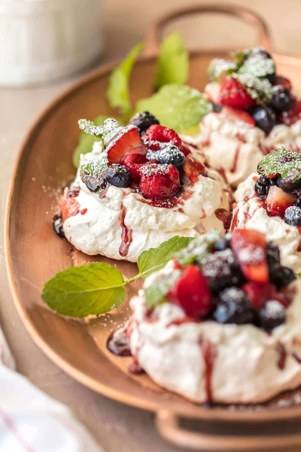 Mini Pavlovas topped with berries, on a serving tray