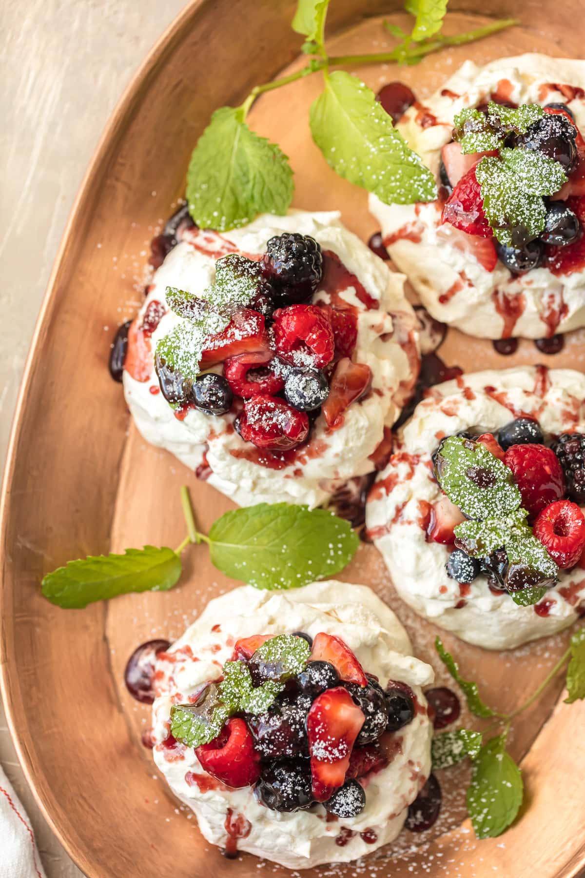 Mini Pavlovas - Meringue desserts topped with berries on a serving tray