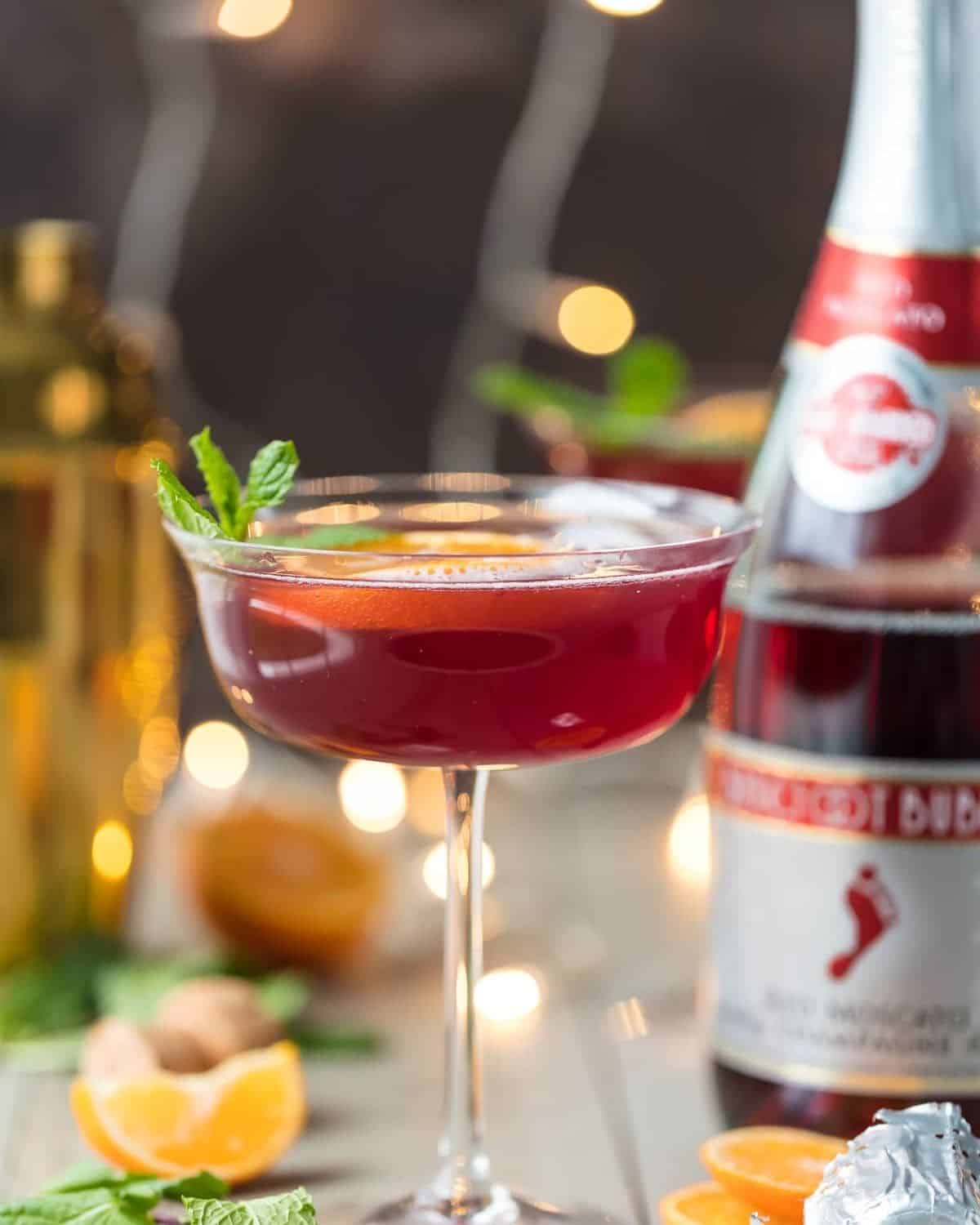 Flirtinis are a fun drink perfect for festive occasions. This Sparkling Holiday Flirtini is so fun, so pretty, and so delicious! It's made from cranberry and pineapple juice mixed with orange vodka, and topped off with red Moscato champagne. It's the perfect holiday cocktail recipe for Christmas or New Year's Eve! Sparkling holiday flirtini in a martini glass.