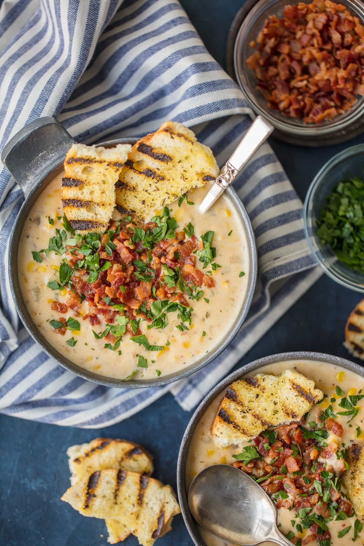 A bowl of bacon corn chowder topped with bacon, served with toasted bread