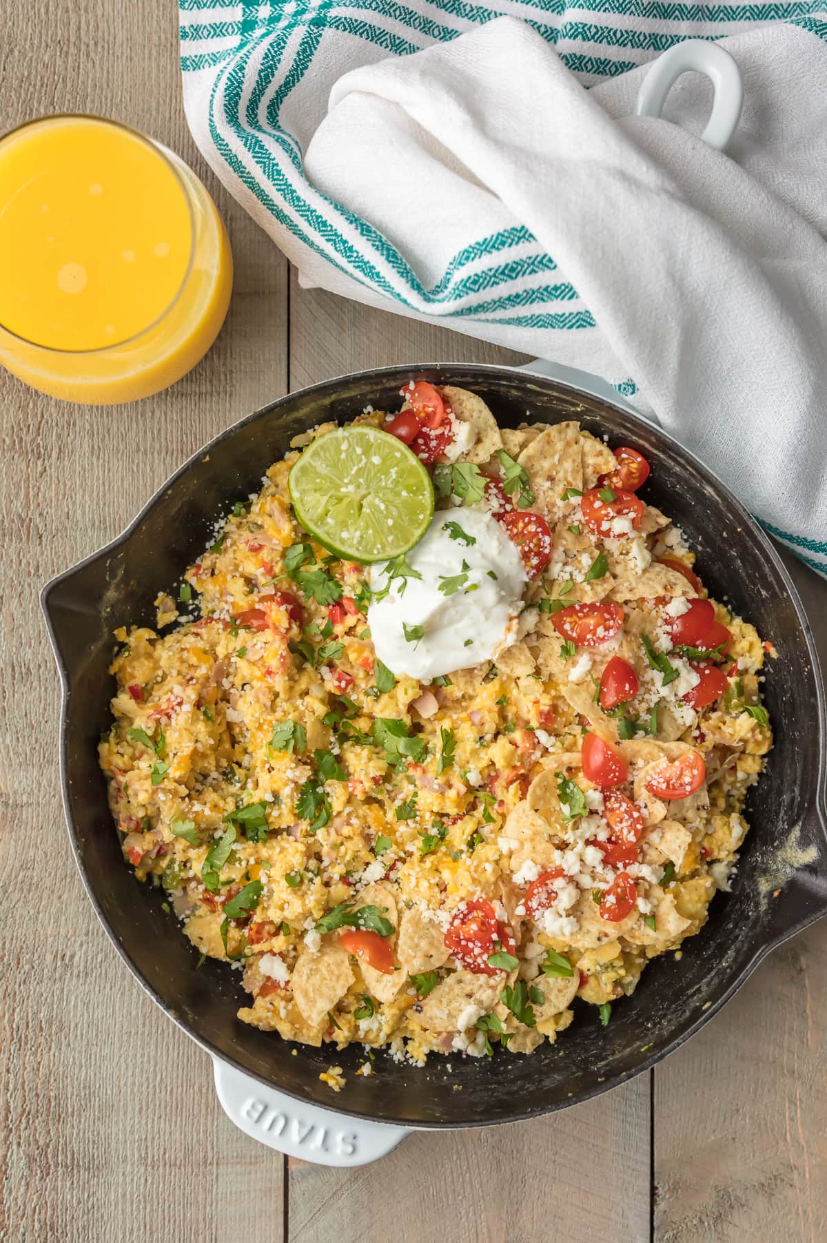 Tex Mex Migas recipe in a skillet, next to a dish towel and a glass of orange juice