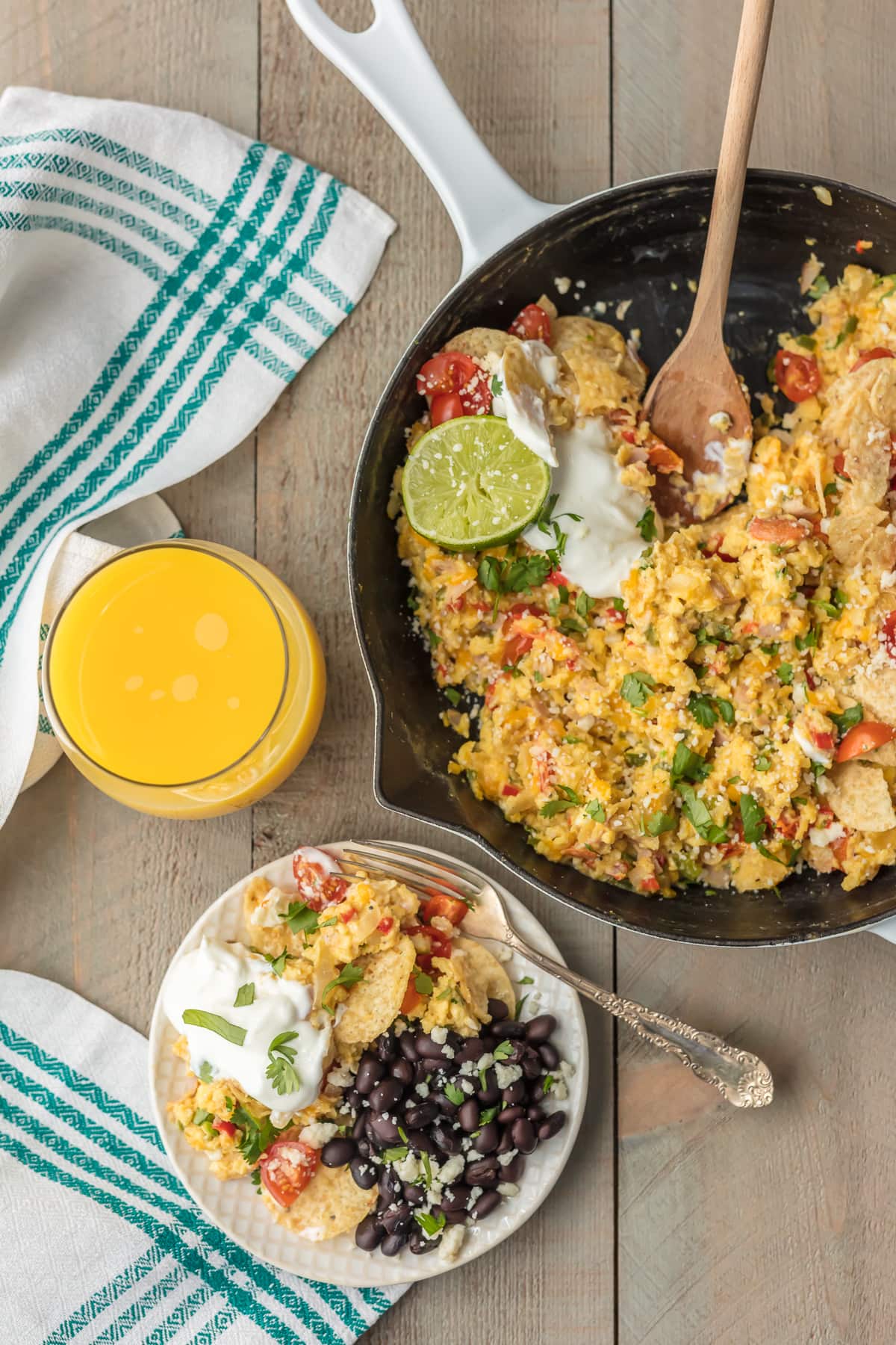 A skillet of cheesy migas, next to a plate of migas and black beans