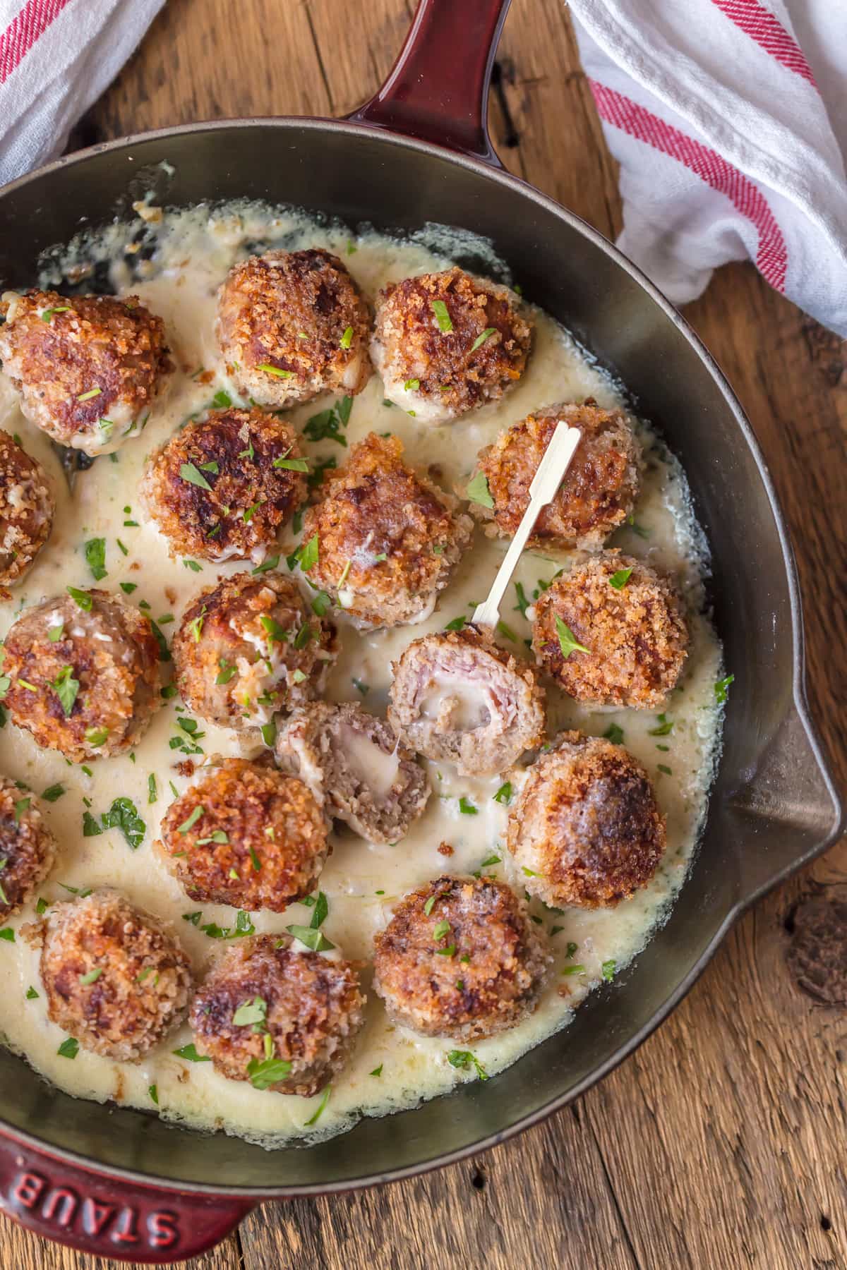 Chicken meatballs stuffed with ham and swiss cheese, sitting in a skillet with dijon sauce