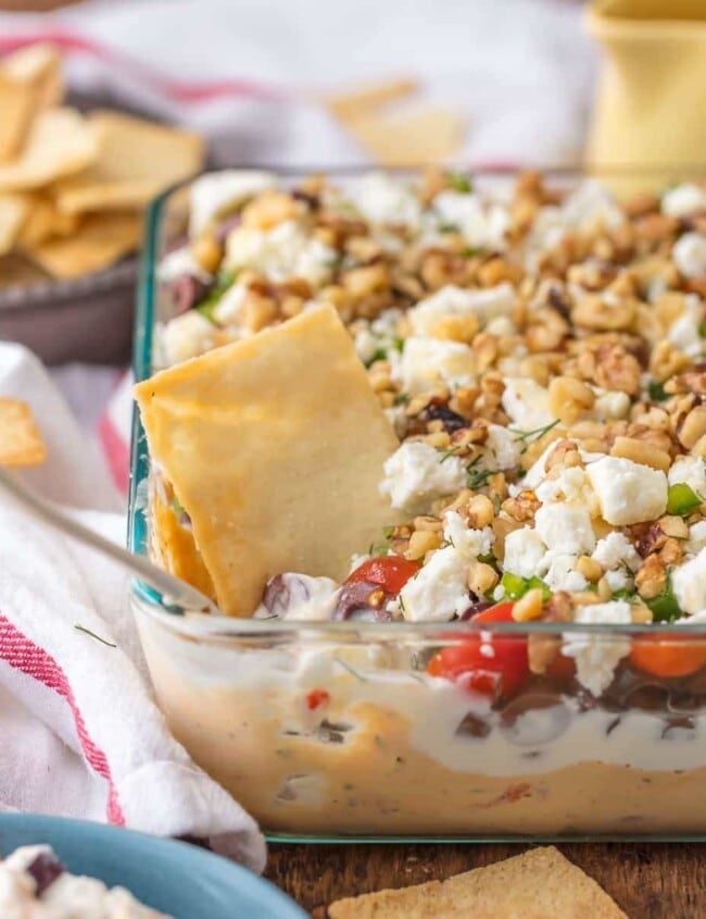 7 Layer GREEK DIP is a fun twist on a classic appetizer. This delicious 7 layer dip recipe is the perfect shareable appetizer for Christmas, New Year's Eve, or for tailgating. Seven delicious layers of hummus, greek yogurt, feta, and all of the best Mediterranean inspired ingredients make it a seriously addicting dip!
