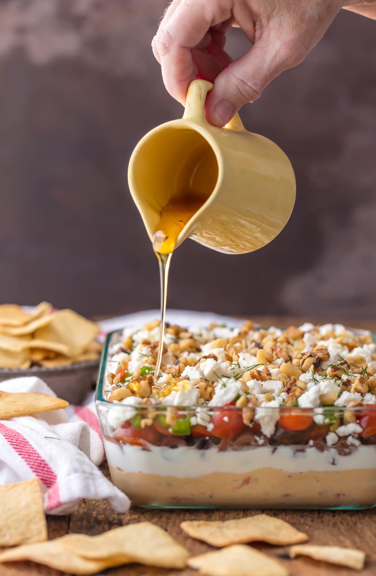Pouring honey over a 7 layer greek dip
