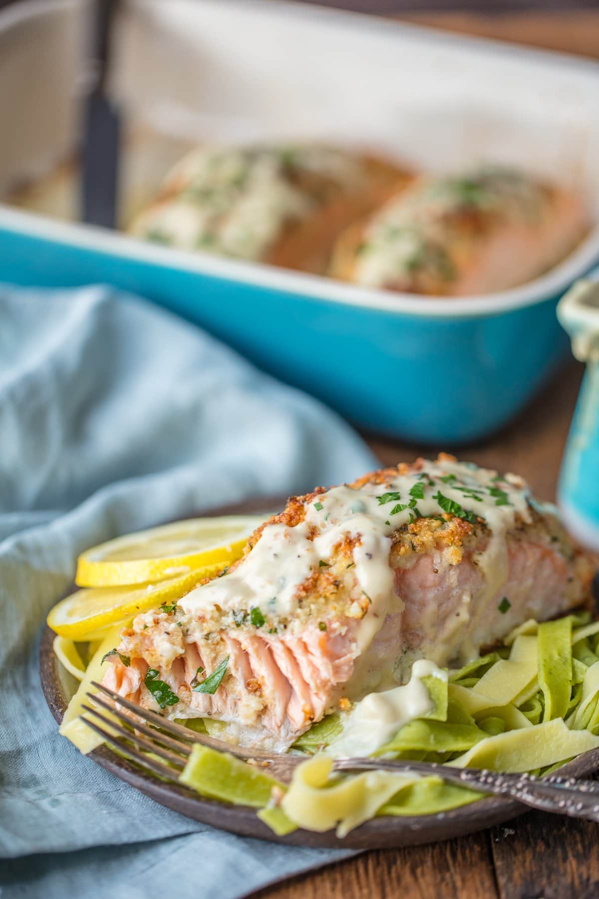 A plate of baked salmon with the baking dish in the background