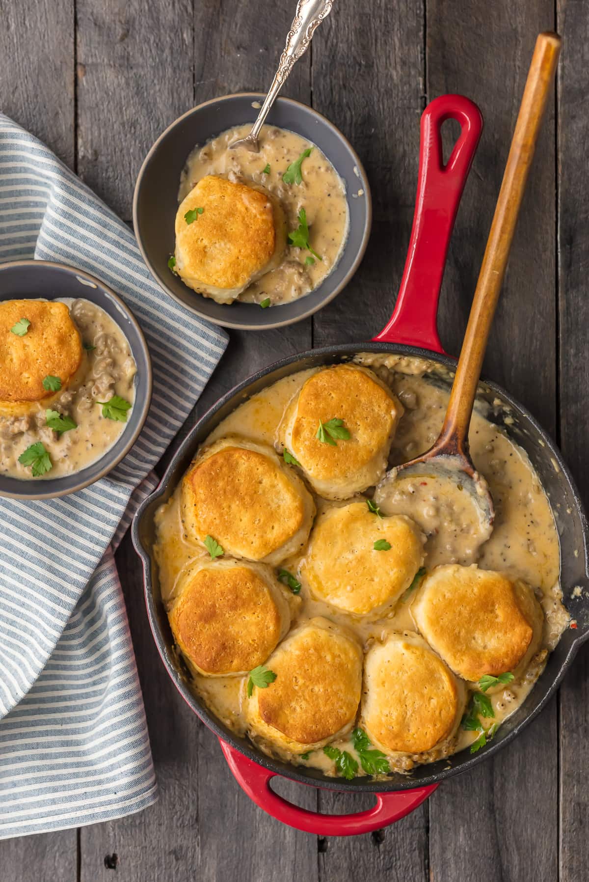 Sausage Biscuit Gravy Cobbler in a skillet, next to two bowls filled with biscuits and gravy