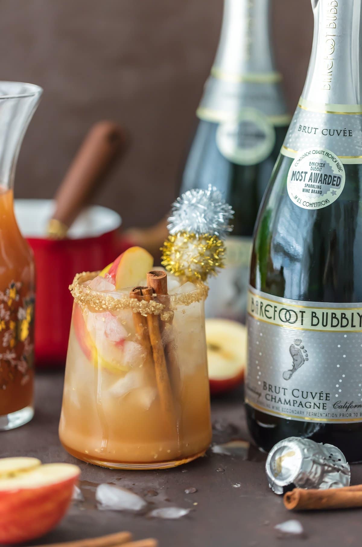 Champagne and apple cider cocktail in a glass with cinnamon sticks and apple slices