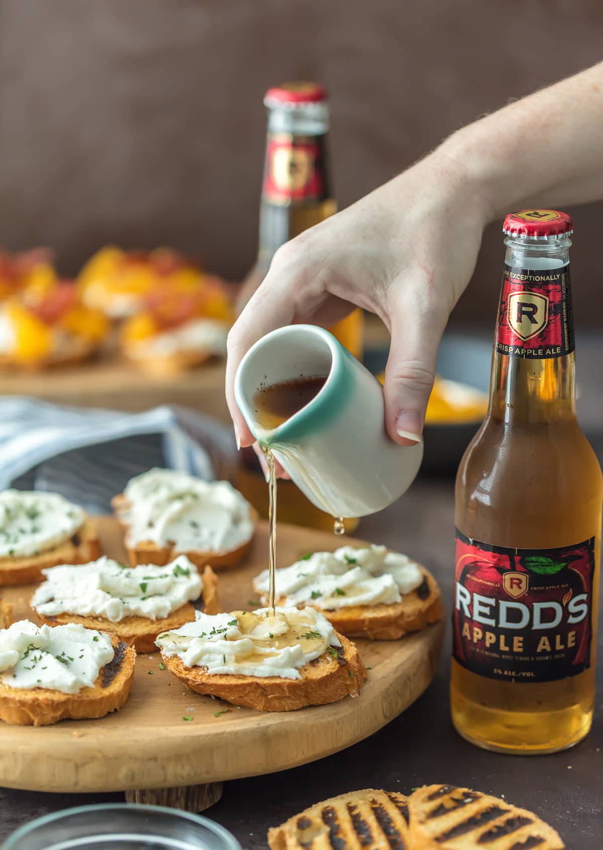 Goat Cheese Crostini on a wooden serving platter, with two Redd's Apple Ales