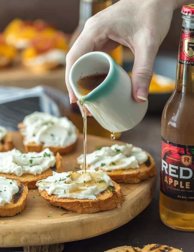 whipped goat cheese bruschetta with honey being poured