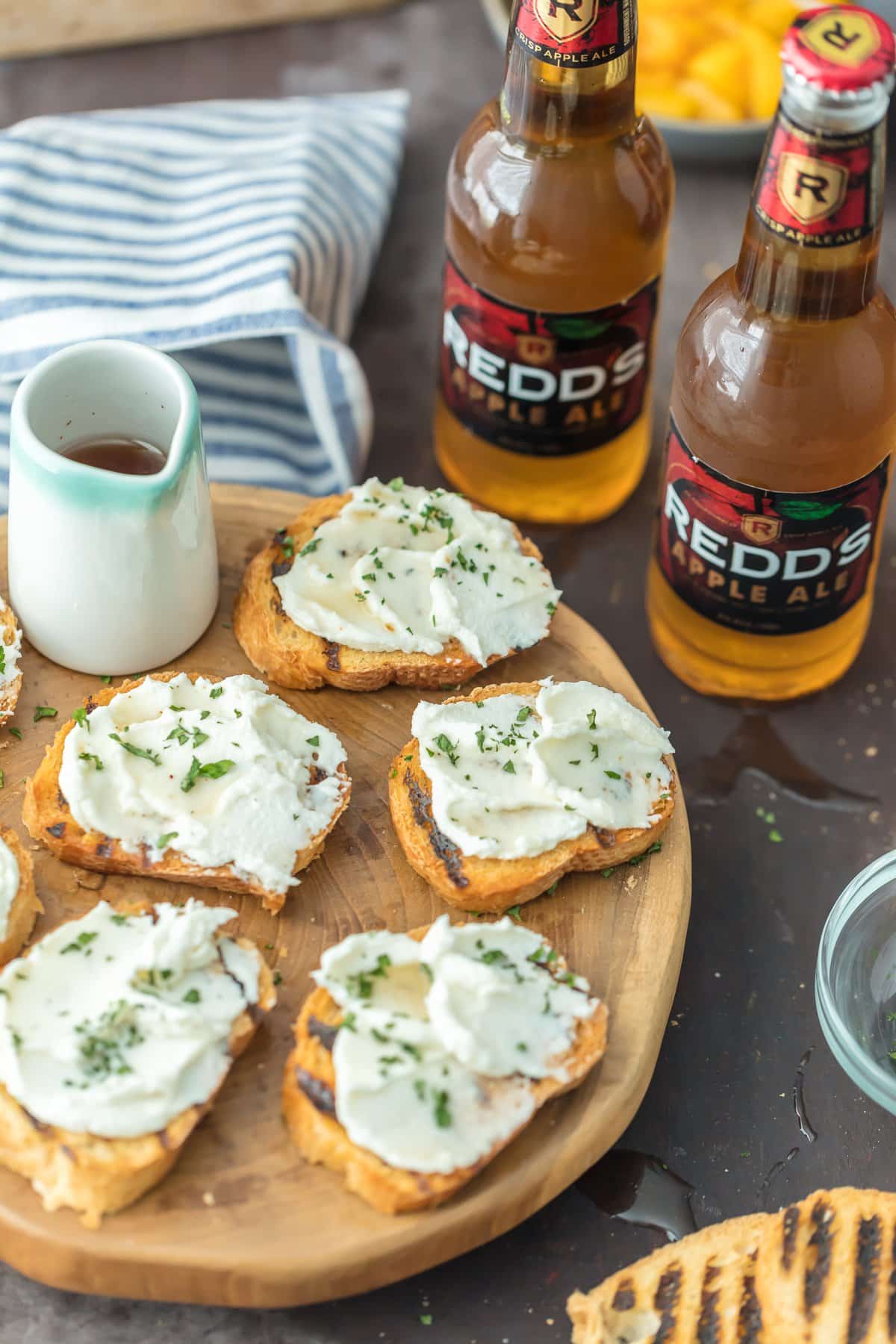 Goat Cheese Crostini on a serving platter next to two bottles of beer