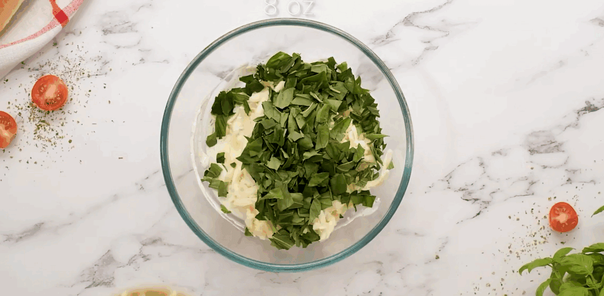 Adding cheese and fresh basil to the bowl. - 6
