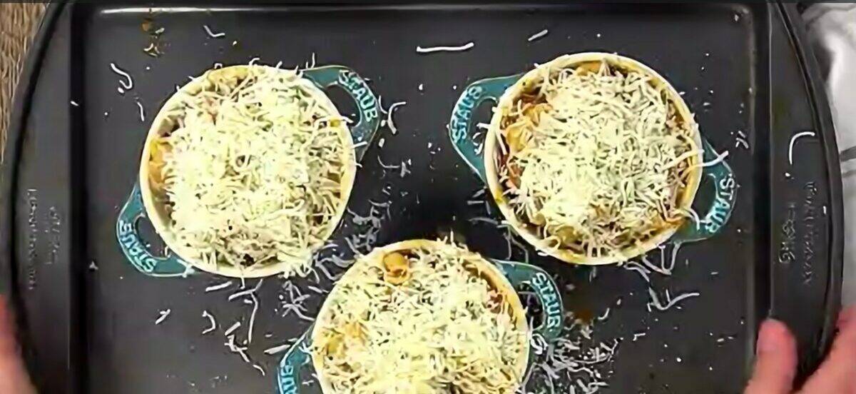 3 bowls of soup topped with cheese on a rimmed baking sheet. 
