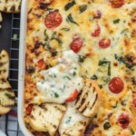 baking dish with cheesy caprese dip with toasted bread