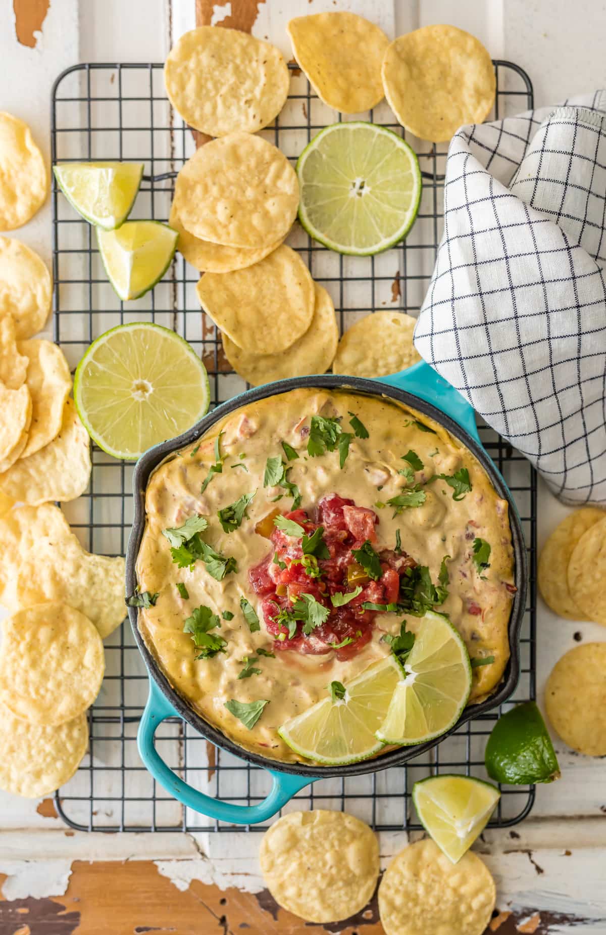A cooling rack with a dish of dairy free queso on top, and tortilla chips scattered across it