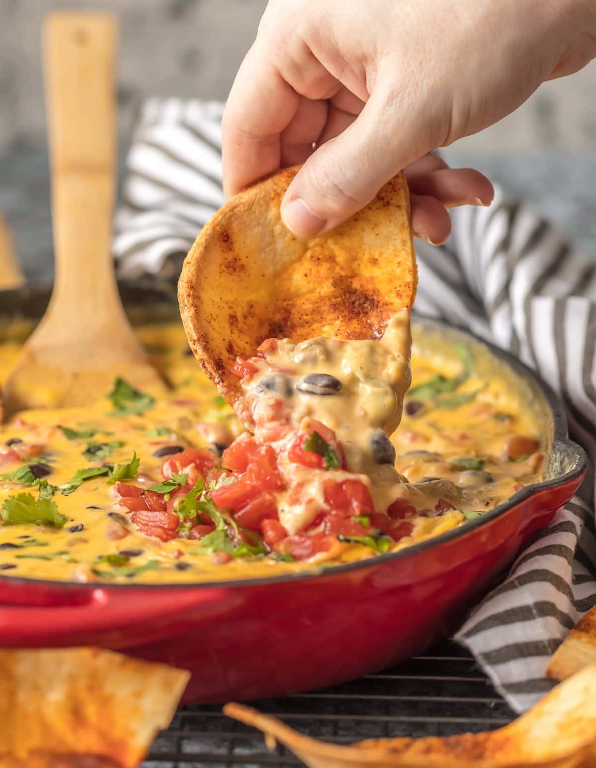 Taco boat chip dipping into velveeta cheese dip loaded with rotel, sausage, black beans, and more