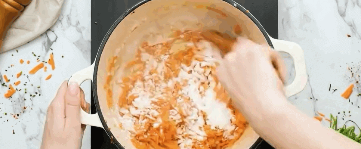 Adding flour to carrot and onion mixture. 