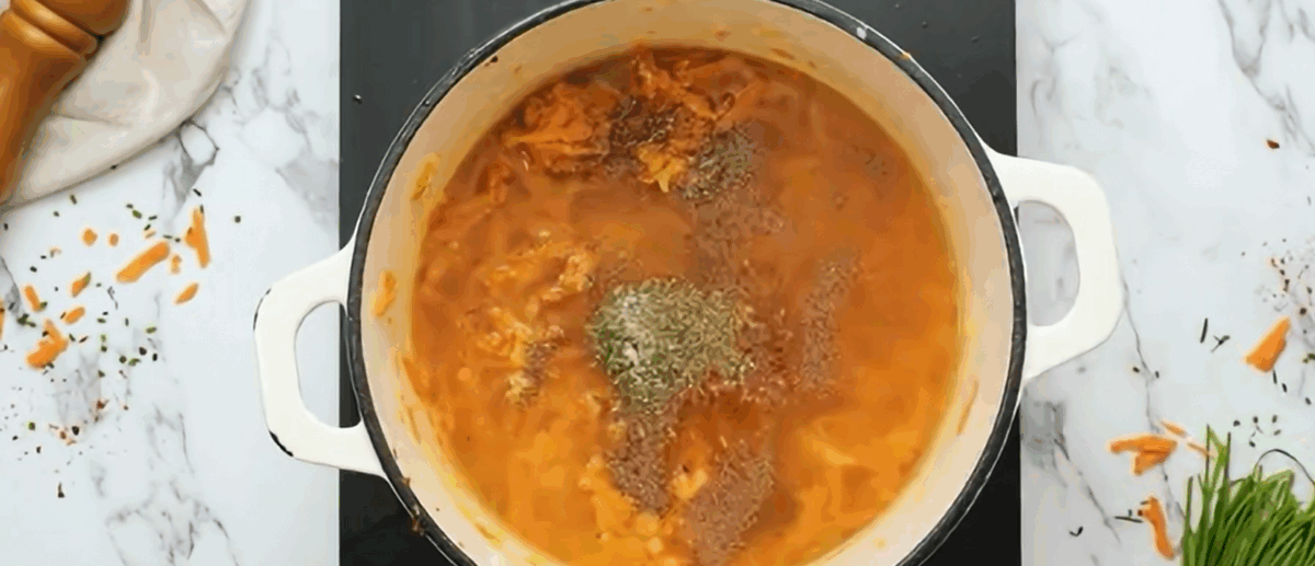 Adding broth and spices to the soup. 