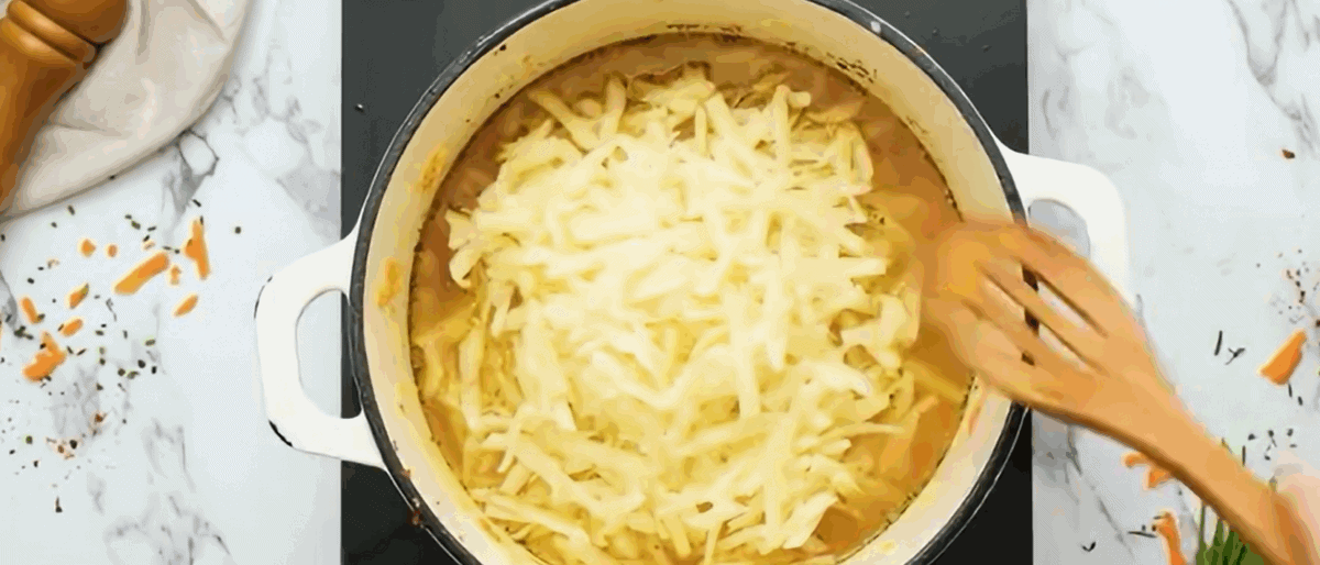 Adding shredded hash browns to the soup pot. 