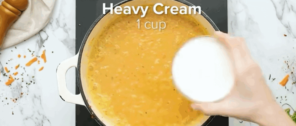 Adding cream and milk to pureed soup.
