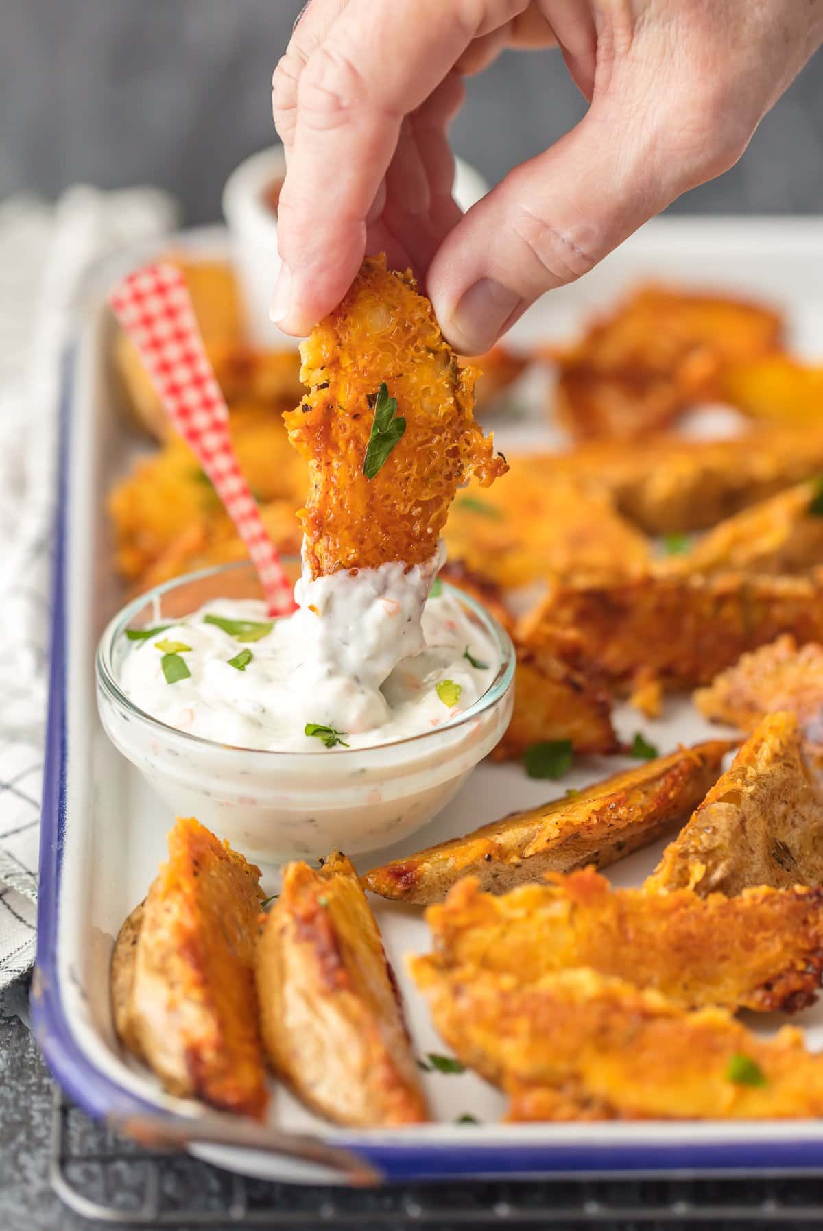 Dipping crispy potato wedges into dipping sauce