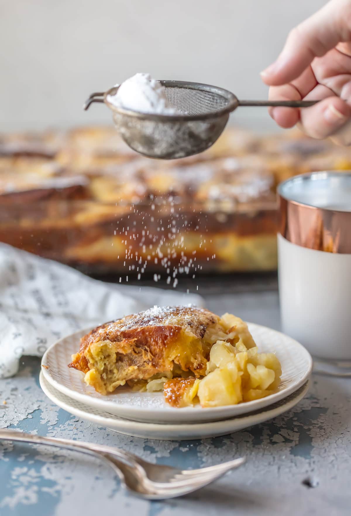 Sprinkling baked french toast with powdered sugar