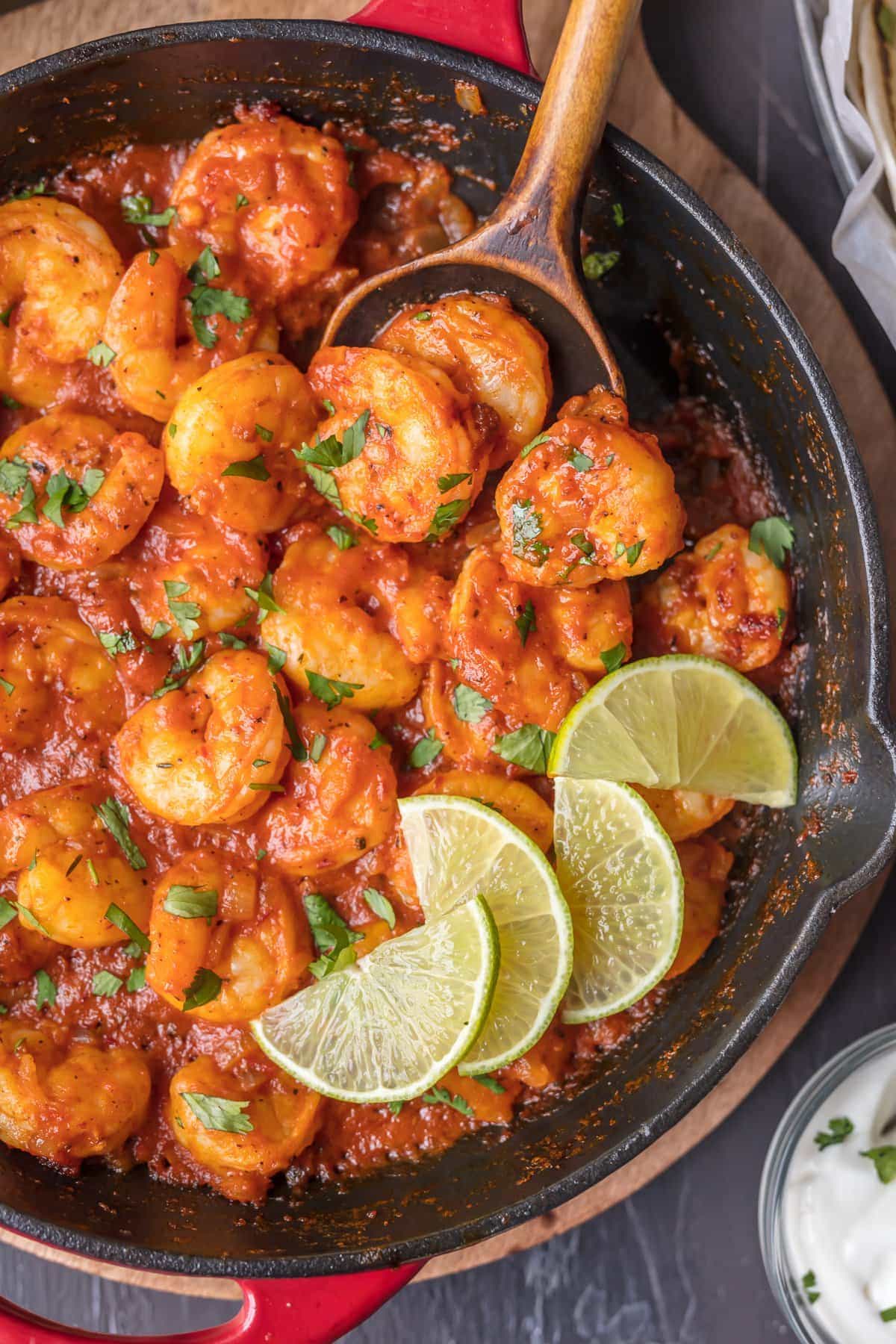 Chipotle shrimp in a skillet with lime wedges