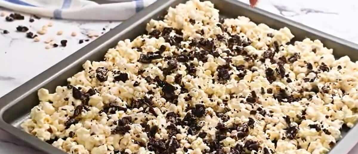 Chocolate covered popcorn and Oreo cookie chunks on a baking sheet.