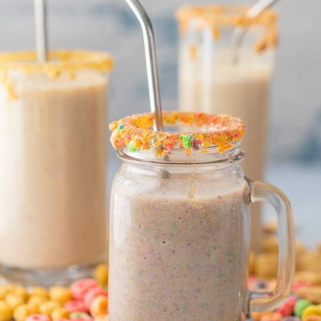 three smoothies in glasses surrounded by cereal