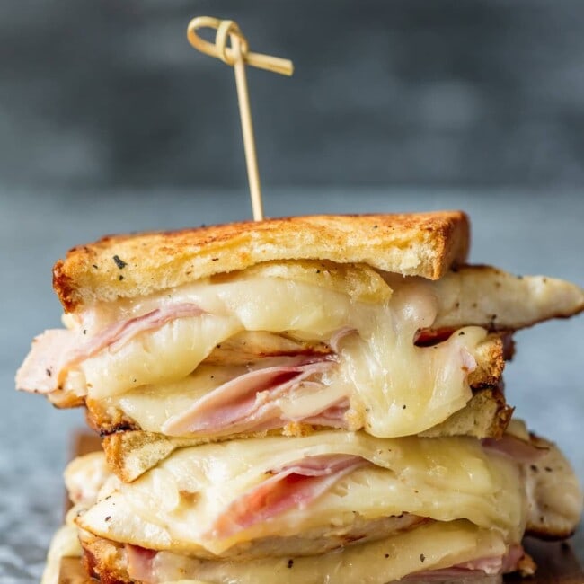 side view of grilled chicken bleu sandwich on a wooden platter