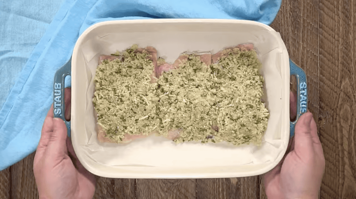 raw salmon filets crusted with parmesan breadcrumbs in a baking pan.