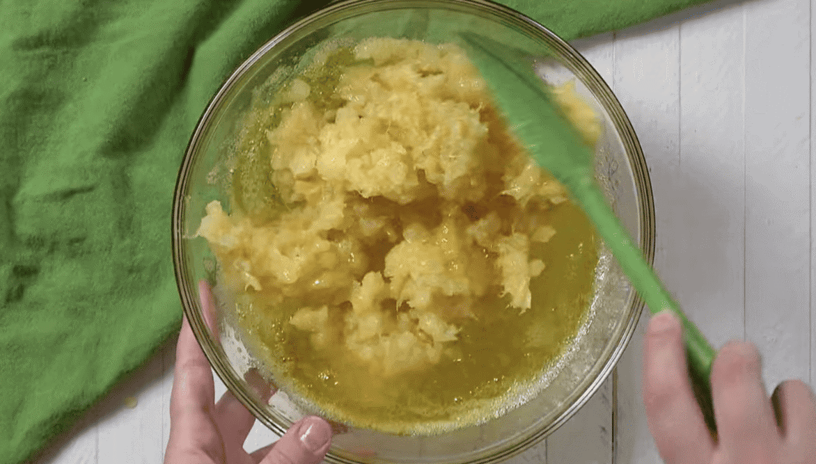 Adding crushed pineapple to the Jello Mixture in a glass bowl. 