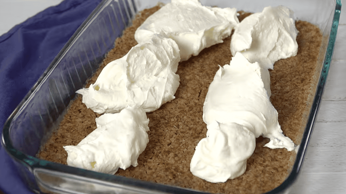 whipped topping dolloped over pretzel crust in a glass dish.