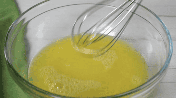 yellow liquid in a glass bowl with a whisk.