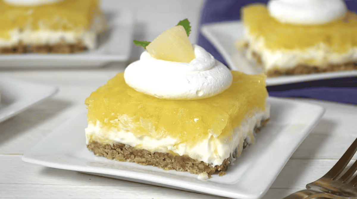 a serving of pineapple pretzel salad on a white plate with whipped cream, pineapple, and mint.