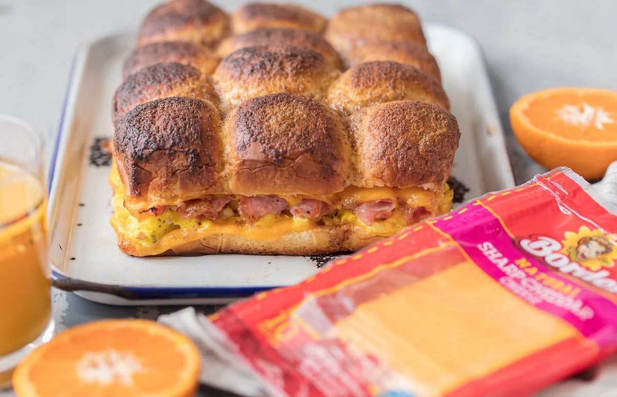 Ham, egg, and cheese sandwiches on baking tray next to a package of cheese slices