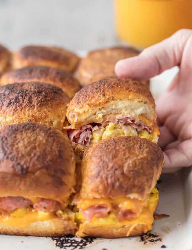 These CHEESY BAKED BREAKFAST SLIDERS are so easy and perfect for feeding a crowd! Baked on Hawaiian rolls with layers of ham, egg, and cheese and topped with a brown sugar dijon butter sauce! TOO GOOD!