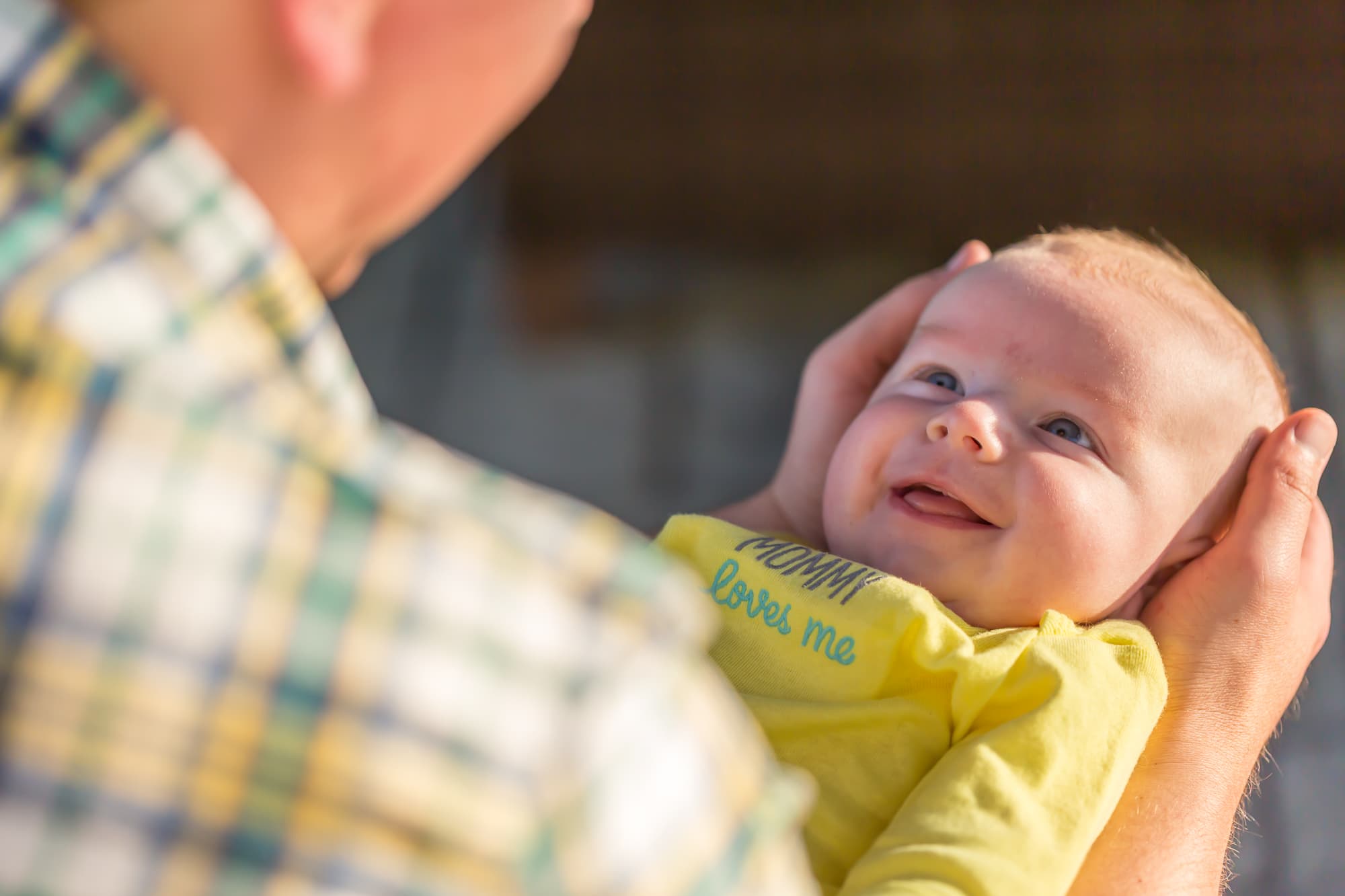baby in yellow onesie smiling up at father