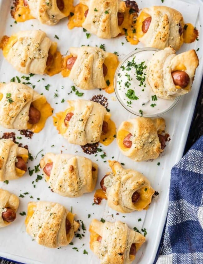 Pigs in a Blanket with Cheese and Parmesan Ranch Butter will be all the rage at your next party. This Pigs in a Blanket Recipe is easy, fun, and oh so delicious. If you've wondered How to Make Pigs in a Blanket, these Lil' Smokies wrapped in sharp cheddar, crescent roll dough, and brushed with parmesan ranch butter are sure to be a hit.