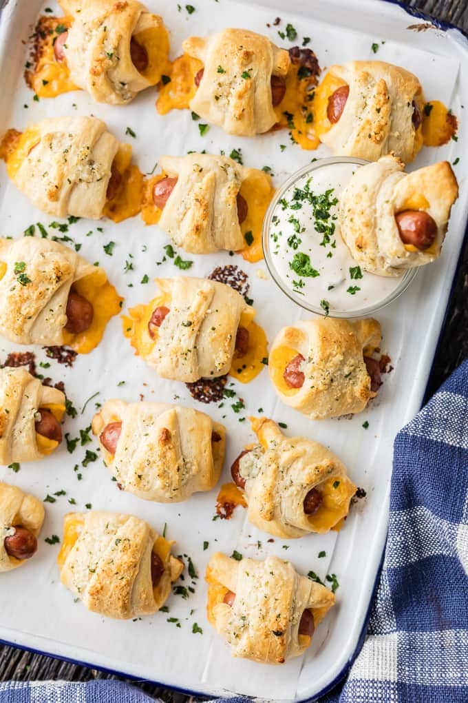 These CHEESY PIGS IN A BLANKET with RANCH PARMESAN BUTTER will be all the rage at your next party. They're easy, fun, and oh so delicious. Lil' Smokies wrapped in sharp cheddar, puff pastry, and brushed with parmesan ranch butter are sure to be a hit.