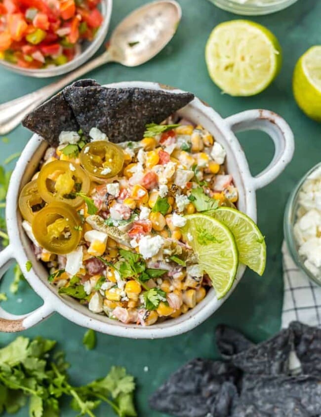 This MEXICAN STREET CORN SALSA recipe is my favorite spicy corn dip, just perfect for every occasion! Roasted corn, feta, lime juice, sour cream, cilantro, pico de gallo, and more!