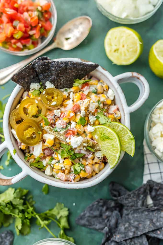This MEXICAN STREET CORN SALSA recipe is my favorite spicy corn dip, just perfect for every occasion! Roasted corn, feta, lime juice, sour cream, cilantro, pico de gallo, and more! MEXICAN STREET CORN SALSA with blue corn chips