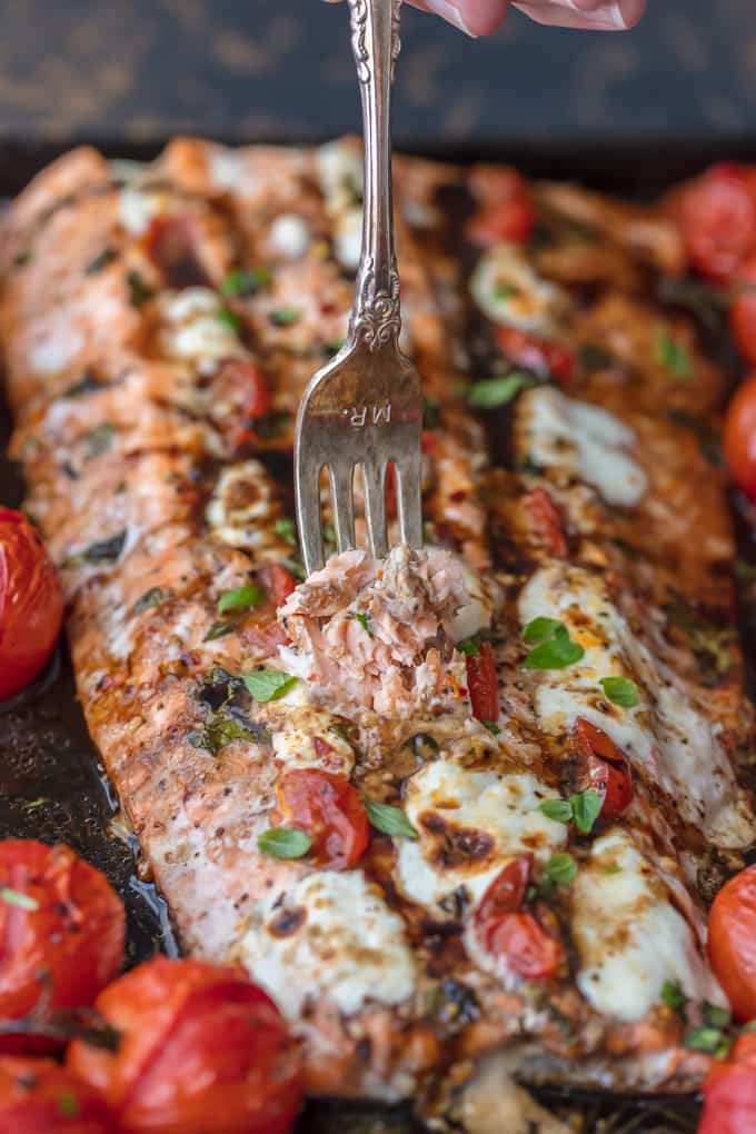 This Caprese Stuffed Salmon recipe is cheesy, delicious, and made on one pan! Baked salmon stuffed with tomato & mozzarella, paired with balsamic tomatoes. Baked salmon one pan meal with roasted tomatoes
