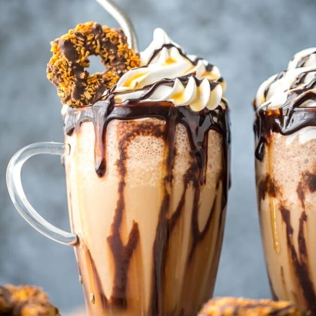 frozen samoa cookie cold brew in a glass topped with a cookie, whipped cream, caramel, and chocolate syrup