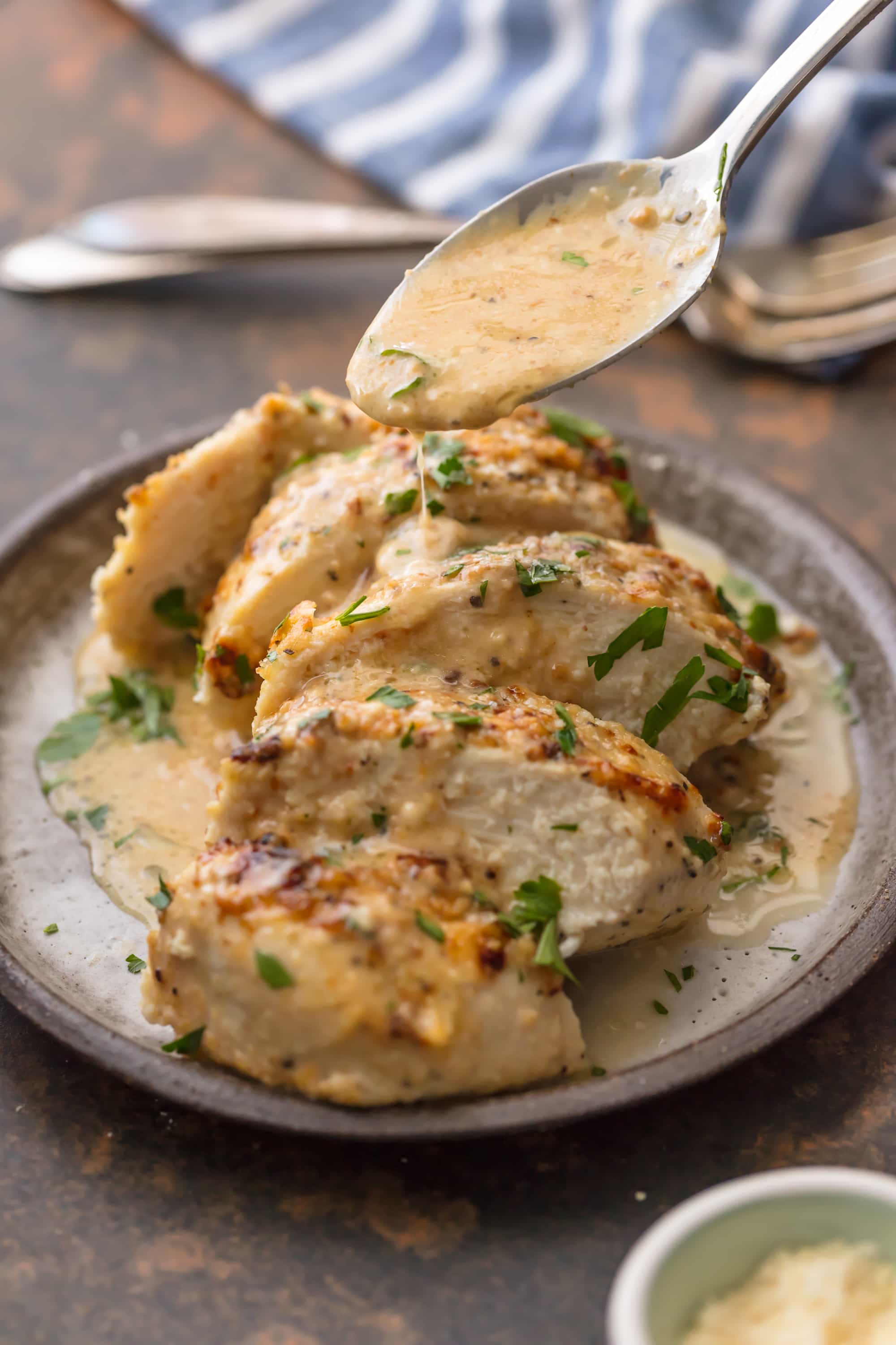 spoon drizzling creamy sauce over sliced chicken breast