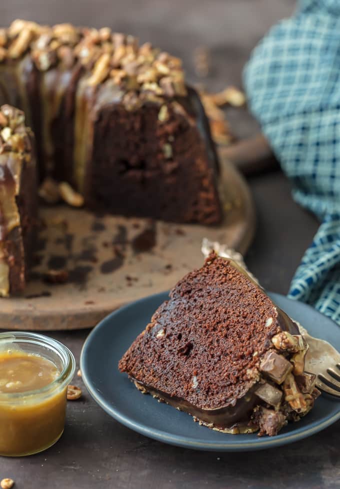 Slice of Turtle Brownie Cake on a plate next to full cake