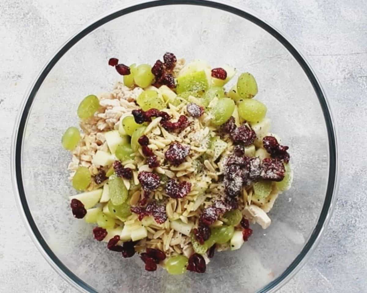 Ingredients to make chicken salad in a glass bowl.