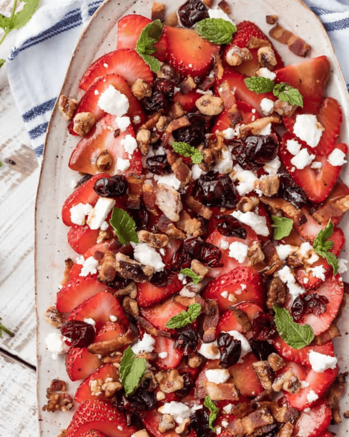 This STRAWBERRY BACON SALAD with HONEY LIME BALSAMIC VINAIGRETTE salad dressing is the perfect salad for summer. Fresh, sweet, savory, and rich, with feta, pecans, and mint on top. Strawberry Bacon Salad with Honey Lime Balsamic Vinaigrette on a platter.