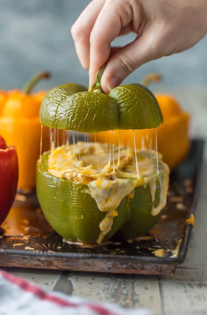 This STUFFED PEPPERS RECIPE is our go-to easy dinner recipe. These Cheesy Enchilada Stuffed Peppers are loaded with beef, green chiles, onions, enchilada sauce, and so much cheese! You won't believe how easy this stuffed bell pepper recipe is and how much your entire family will love it. lifting the top off of enchilada stuffed peppers recipe