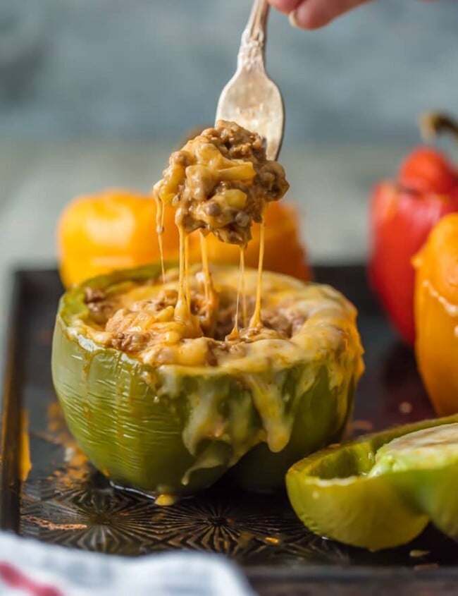 This STUFFED PEPPERS RECIPE is our go-to easy dinner recipe. These Cheesy Enchilada Stuffed Peppers are loaded with beef, green chiles, onions, enchilada sauce, and so much cheese! You won't believe how easy these are and how much your entire family will love them. 